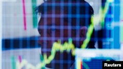 FILE - A trader looks up at a chart on his computer screen while working on the floor of the New York Stock Exchange, July 11, 2013. 