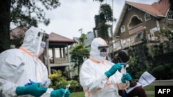 Staff members of the Congolese Ministry of Health perform a COVID-19 test at a private residence in Goma, northeastern Democratic Republic of Congo, on March 31, 2020. 
