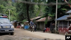 Local residents ride a motorcycle past a police checkpoint in Myanmar's border town of Maungdaw, Rakhine State, Oct. 13, 2016.