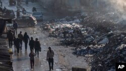 গাজা সিটিতে আবর্জনার স্তূপের পাশ দিয়ে হেঁটে যাচ্ছে ফিলিস্তিনিরা। ১২ ফেব্রুয়ারি, ২০২৫। 