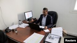 An employee of the High National Election Commission sits inside his office at the headquarters of the Commission in Benghazi, Libya, Dec. 16, 2021. 