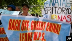 FILE - Protesters display placards in front of the Chinese Consulate to protest China's alleged continuing "militarization" of the disputed islands off the South China Sea including a plan to build a monitoring station on Scarborough Shoal, March 24, 2017. W.P.S. in the placard stands for West Philippine Sea.