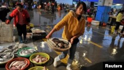 FILE - A vendor carries a basket of fresh fish at a seafood market in Quanzhou, Fujian province, China, Dec. 9, 2013. Joining international sanctions against North Korea, China issued a notice earlier this week stopping imports of iron, lead, coal and seafood from Pyongyang.