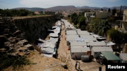 FILE - Refugees and migrants make their way at the Souda municipality-run camp, on the island of Chios, Greece, Sept. 7, 2016. 