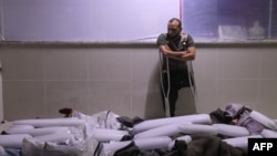 A Syrian amputee looks at bodies of civilians reportedly killed in regime airstrikes on Muhambal, in northern Idlib province, July 6, 2019. A Syrian regime bombardment killed 14 civilians, including seven children, a war monitor said.