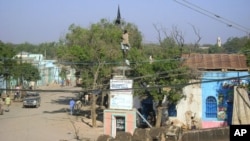 A man climbs onto a Somali university building to take down an Al-Shabab flag in the center of Baidoa, a day after the town was seized by Ethiopian troops and allied Somali government forces on February 23, 2012.