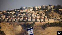 FILE - An Israeli flag is seen near the West Bank Jewish settlement of Maaleh Adumim on the outskirts of Jerusalem.