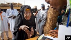 FILE - A Nigerian woman validates her voting card with a fingerprint reader so she can vote later in the day in the town of Daura, March 28, 2015. 