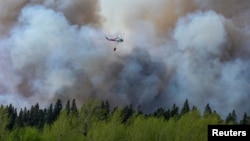 FILE - Water droppers battle an out of control forest fire after the city of Prince Albert declared a state of emergency over a fast-moving wildfire, prompting some residents to evacuate, in Prince Albert, Saskatchewan, Canada, May 18, 2021.