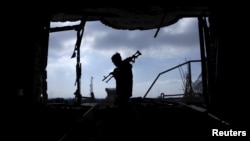 FILE - An Afghan policeman inspects a building used by insurgents after an operation near the Indian consulate in Mazar-i-Sharif, Afghanistan, Jan. 5, 2016. 