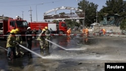 Afghan workers clear debris from the site of a car bomb blast at the entrance gate to the Kabul airport, Afghanistan, Aug. 10, 2015. 