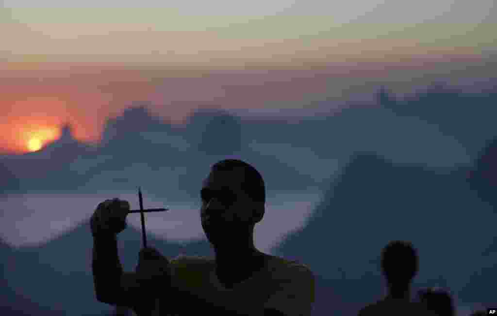 A man makes a cross with two pencils during a protest promoted by the NGO Rio de Paz, in solidarity with those killed in an attack at the Paris offices of the weekly newspaper Charlie Hebdo, in Niteroi, Brazil, Jan. 8, 2015.