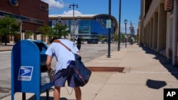 A postal worker empties a box near the Fiserv Forum on Aug. 18, 2020, in Milwaukee. 