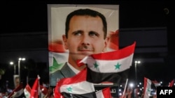 Les Syriens agitent des drapeaux nationaux et portent un grand portrait de leur président alors qu'ils célèbrent dans les rues de la capitale Damas, un jour après une élection qui devrait donner à l'actuel président Bashar al-Assad un quatrième mandat, le