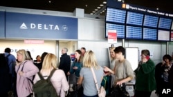 Passengers wait in front of the desk of American airline company 'Delta', at the Roissy Charles de Gaulle airport, north of Paris, March 12, 2020. 