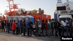 Migrants line up as they are helped by members of Spanish Red Cross after arriving on a rescue boat at the port of Algeciras, southern Spain, July 22, 2018.