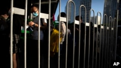 Commuters wearing face masks to protect against the new coronavirus wait in line for buses in the central business district in Beijing, Tuesday, May 19, 2020.