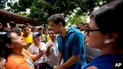 Kandidat dari partai oposisi Carlos Ocariz, yang memperebutkan kursi gubernur negara bagian Miranda, berbicara dengan seorang perempuan saat berkampanye di Guarenas, di pinggiran Caracas, Venezuela, 7 Oktober 2017. 