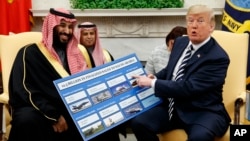 President Donald Trump shows a chart highlighting arms sales to Saudi Arabia during a meeting with Saudi Crown Prince Mohammed bin Salman in the Oval Office of the White House, March 20, 2018, in Washington.
