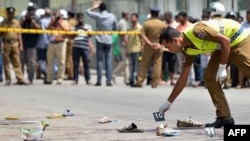 A Sri Lankan police officer examines the scene of a shooting in the capital Colombo, where a woman was killed and 13 others were wounded, July 31, 2015.