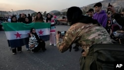 Боєць сирійської опозиції фотографує громадян, які несуть революційний прапор, під час святкування другого дня захоплення міста повстанцями в Дамаску, Сирія, 9 грудня 2024 року.