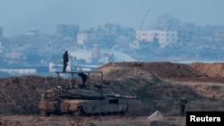 Ahead of a ceasefire between Israel and Hamas, Israeli soldiers stand on a tank parked on the Israeli side of the border with Gaza, Jan. 16, 2025.