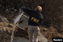 An FBI agent carries debris after an American Airlines flight, operated by affiliate PSA Airlines, collided with a Black Hawk helicopter while approaching Ronald Reagan Washington National Airport and crashed into Potomac River, in Arlington, Virginia, Jan. 30, 2025.