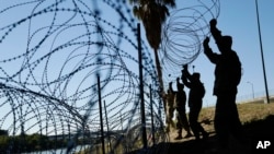 FILE - Members of the U.S. military install multiple tiers of concertina wire along the banks of the Rio Grande near the Juarez-Lincoln Bridge at the U.S.-Mexico border in Laredo, Texas, Nov. 16, 2018. 