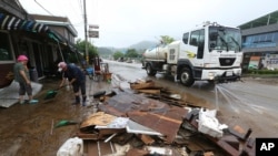 Residents scrape mud away from a damaged house following heavy rains in Cheorwon, South Korea, Aug. 6, 2020.
