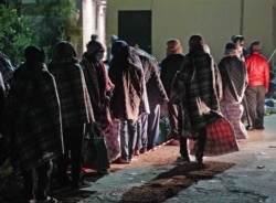 FILE - Migrants return to the Lampedusa reception center after they were unable to board quarantine ship GNV Azzurra due to strong winds, in Lampedusa, Italy, May 11, 2021.
