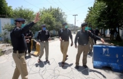 Pakistani police officers stand guard at a checkpoint of a restricted area to help contain the spread of new coronavirus, in Peshawar, Pakistan, June 16, 2020.