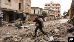 Un homme transporte ses effets personnels dans une rue détruite dans la ville de Sarmin, dans la province d'Idbleb, en Syrie, le 7 février 2020. (Photo AP / Ghaith Alsayed)