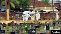 FILE - Doctors and relatives wearing protective gear carry the body of a victim, who lost his battle against the brain-damaging Nipah virus, during his funeral at a burial ground in Kozhikode, in southern India, May 24, 2018.