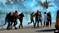 Anti-government protesters run as security forces fire tear gas to disperse them during a clash in Baghdad, Iraq, Jan. 26, 2020. 