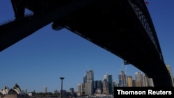 People in protective face masks walk under the Sydney Harbor Bridge during a lockdown to curb the spread of a COVID-19 outbreak in Sydney, Australia, Sept. 3, 2021.