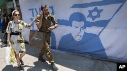 An Israeli soldier and a woman walk past a protest tent calling for the release of captured Israeli soldier Gilad Schalit, near the Prime Minister's residence, in Jerusalem, June 24, 2011.