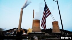 FILE - The U.S. flag flies on a towboat as it passes a coal-fired power-plant on the Ohio River in Moundsville, West Virginia, Sept. 10, 2017. 