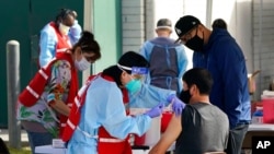 FILE - Health care workers receive a COVID-19 vaccination at Ritchie Valens Recreation Center, Jan. 13, 2021, in Pacoima, Calif. 