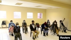 FILE - People wearing protective masks sit ahead of a vaccination, as South Africa rolls out the coronavirus disease (COVID-19) vaccines to the elderly at the Munsieville Care for the Aged Centre outside Johannesburg, South Africa, May 17, 2021.