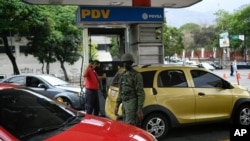 Un soldado hace guardia en una estación de servicio de la compañía petrolera estatal PDVSA donde los conductores esperan en la fila durante horas para llenar en Caracas, Venezuela.