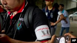 FILE - A local journalist wears an arm band supporting press freedom as he gathers with other journalists during the court appearance of a newspaper editor and a columnist at a township court, June 8, 2017, in Yangon, Myanmar.