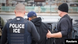 FILE - U.S. Immigration and Customs Enforcement (ICE) officers detain a suspect as they conduct a targeted enforcement operation in Los Angeles, Feb. 7, 2017. 