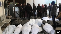 Palestinians stand around relatives killed in the Israeli bombardment of the Gaza Strip at a morgue in Rafah, Feb. 21, 2024.