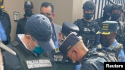 Oficiales de policía esposan al expresidente hondureño Juan Orlando Hernández después de ser detenido por miembros de la Policía Nacional de Honduras, en Tegucigalpa, Honduras, el 15 de febrero de 2022.