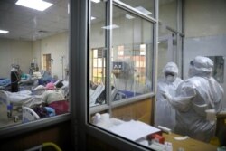 FILE - Medical staff dressed in protective suits talk to each other as they treat coronavirus disease patients at the COVID-19 ICU of Machakos Level 5 Hospital, in Machakos, Kenya, Oct. 28, 2020.