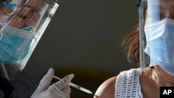 Seorang petugas kesehatan menginokulasi seorang wanita dengan vaksin Sinovac COVID-19 China di pusat vaksinasi sementara di Manila, Filipina, 22 Juni 2021. (AP Photo/Aaron Favila, File)