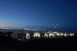 FILE - Tents are set up so people who have registered can get their COVID-19 vaccinations as they drive through the parking lot of the State Farm Stadium in Glendale, Arizona, January 12, 2021.