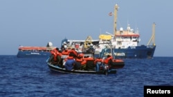 FILE — Crew members from the German NGO migrant rescue vessel Sea-Watch 3 give life jackets to migrants in international waters in the Mediterranean Sea, Aug. 1, 2021. Officials from Cyprus, Greece, Italy, Malta and Spain say more resources are needed to address migration.