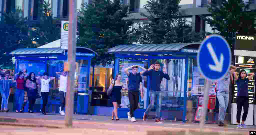 Evacuated people from the shopping mall walk with their hands up in Munich on July 22, 2016 following a shooting earlier.