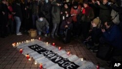 Migrants' rights activists stand next to a banner reading "309 dead on the France UK border since 1999," outside Calais, France, Nov. 25, 2021. At least 27 migrants died when their boat sank in a bid to cross the English Channel, a French government official said Nov. 24, 2021.